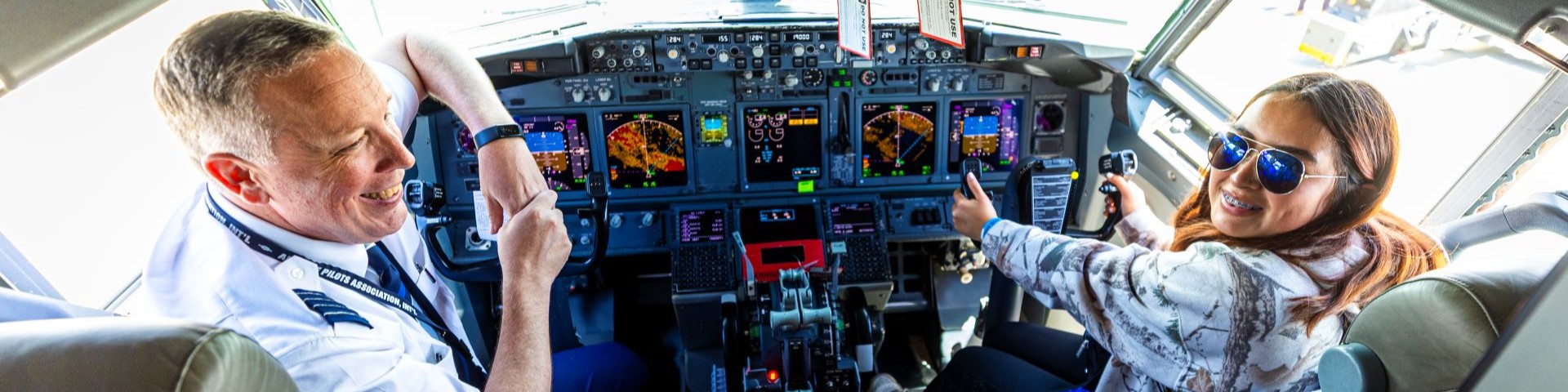 A pilot and a young person in the cockpit of an airplane, engaging in a discussion about aviation careers at aviation day.